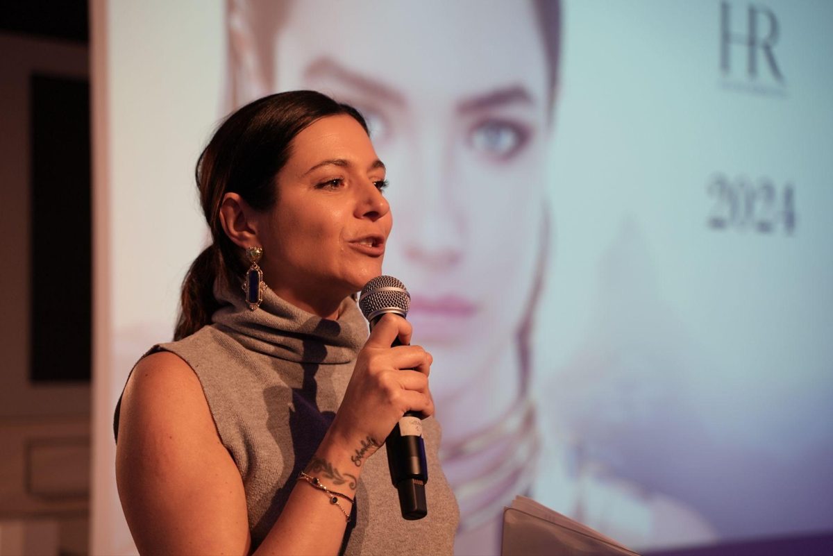 Ginny l'Astrologa parla al microfono durante uno speech